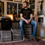 A man sitting on a stack of records